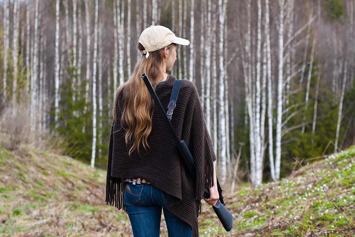 Woman with a shotgun walking in the mountains