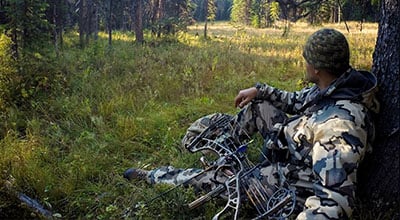 Man sitting with crossbow hunting elk