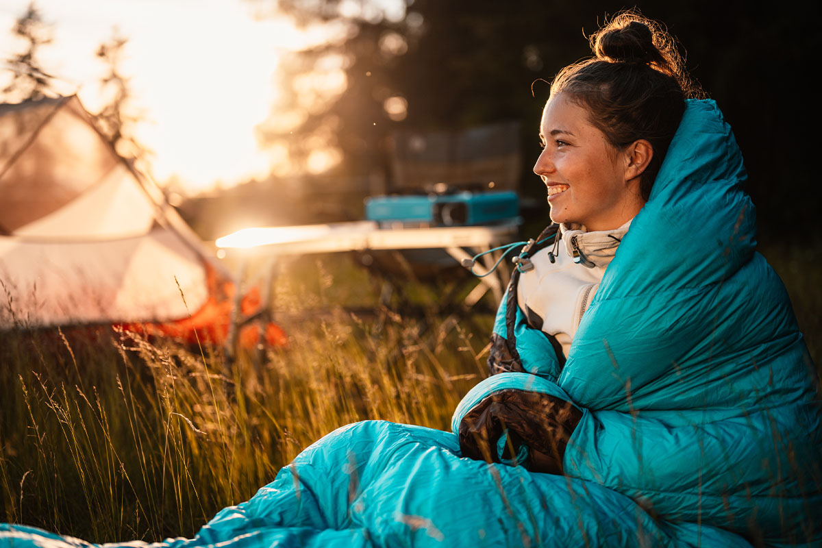 woman in a sleeping bag sitting by a tent