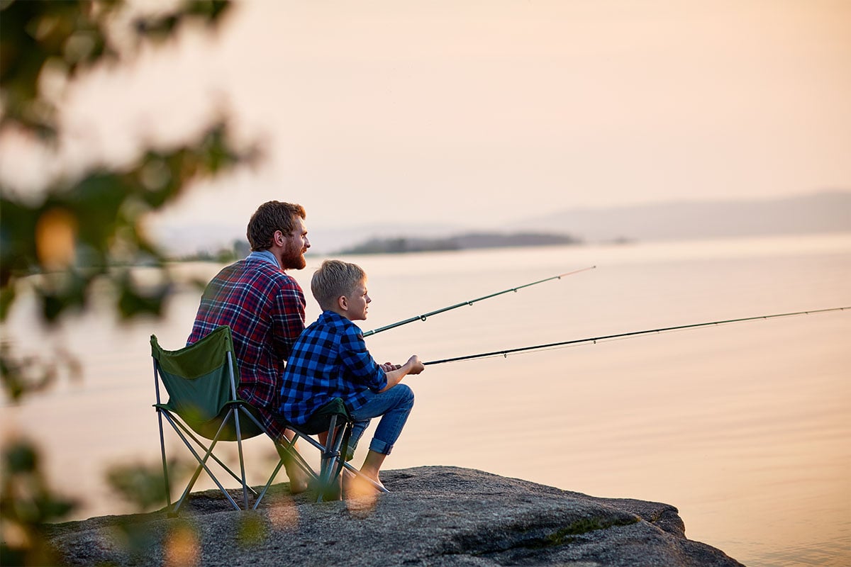 Man fishing with child on a lake