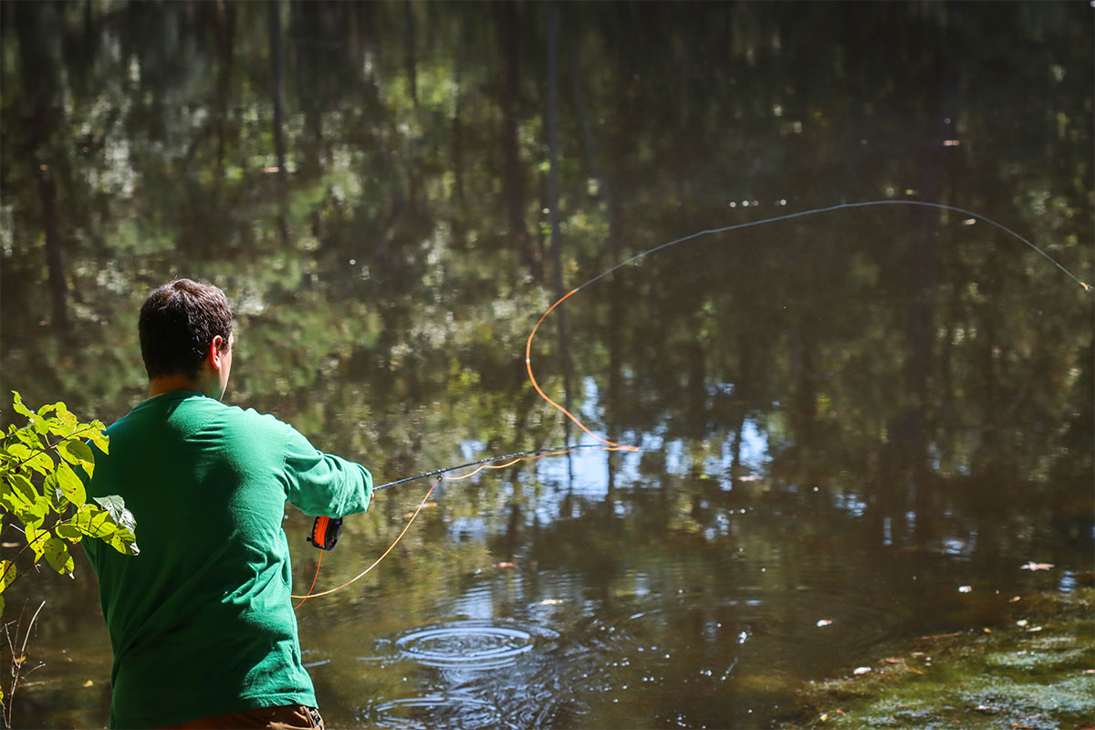 Man flyfishing for smallmouth bass fish in a pond