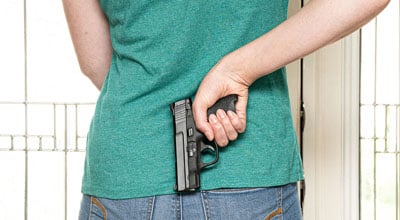 woman holding a gun behind her back