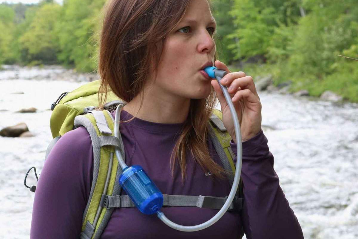 Woman hiking, using hydration pack