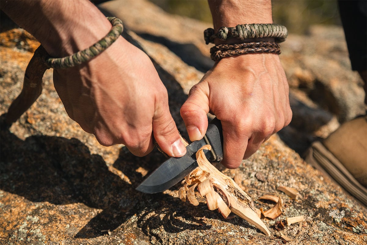 Man cutting a branch with a knife