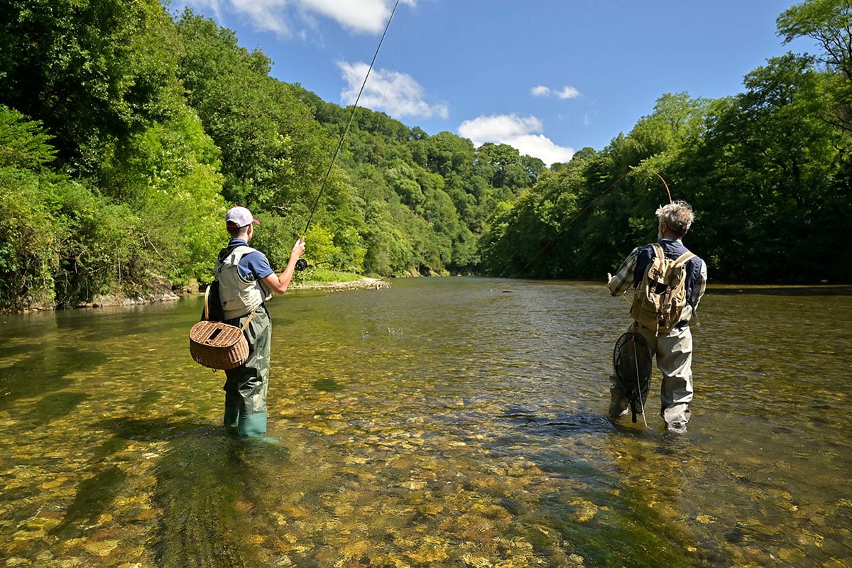 Two men fly fishing in the summertime in the shallows