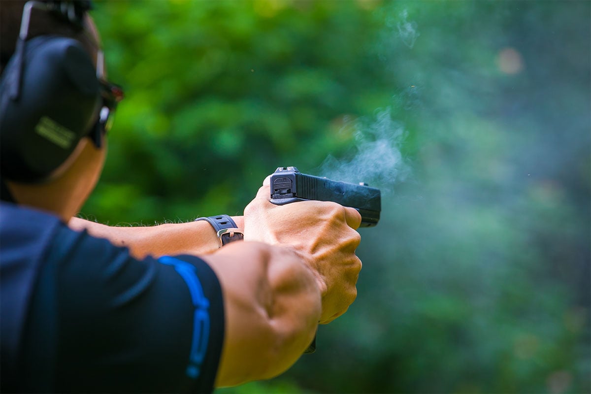 Man shooting a pistol in a field