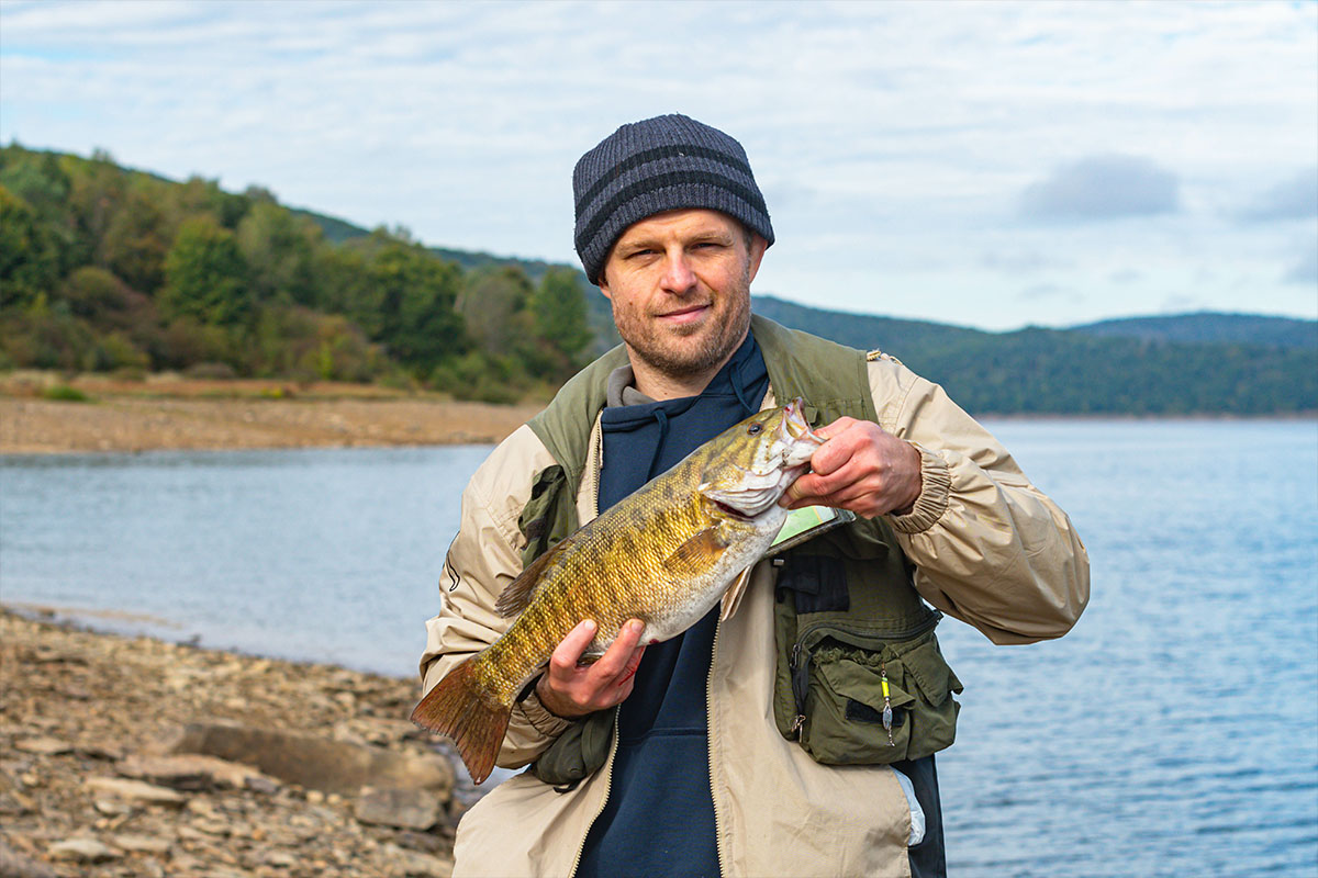 man with smallmouth bass at a lake
