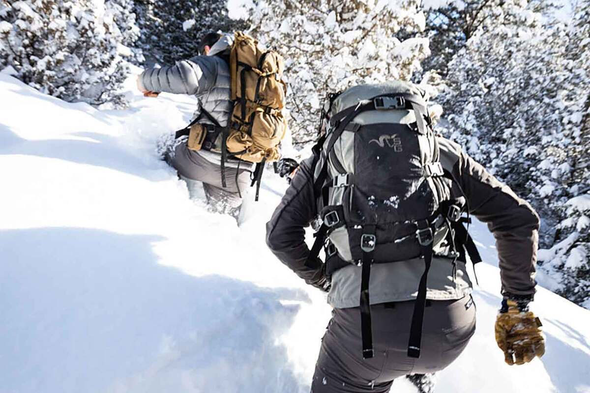 two men hiking in the snow with backpacks