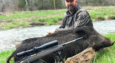 Man with hog and 300 winchester magnum rifle