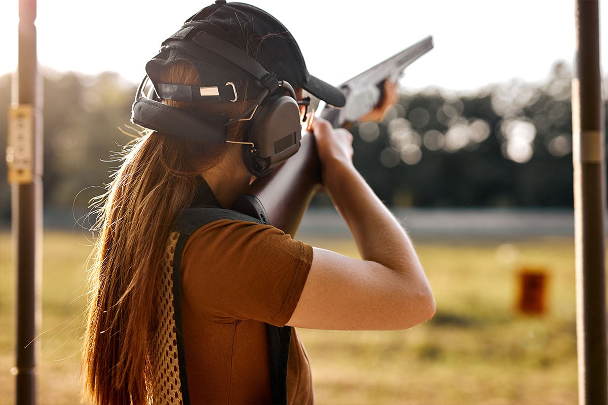 Woman shooting target with shotgun