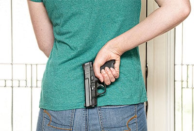 woman holding handgun behind back