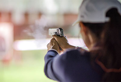 woman shooting handgun at range