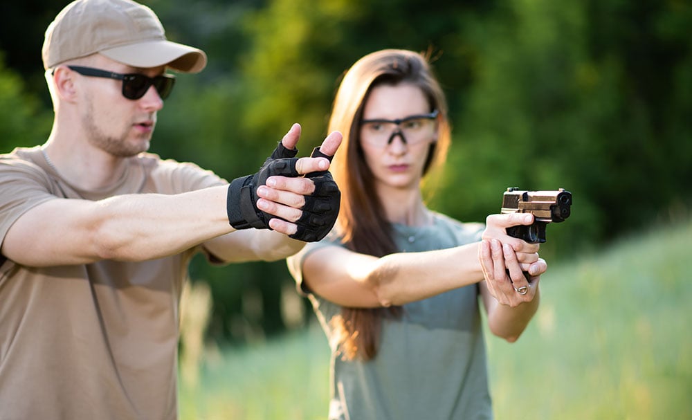 woman shooting handgun with instructor