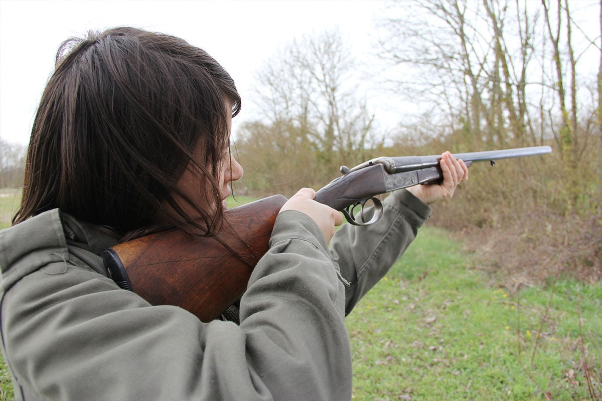 Woman shooting shotgun in a field